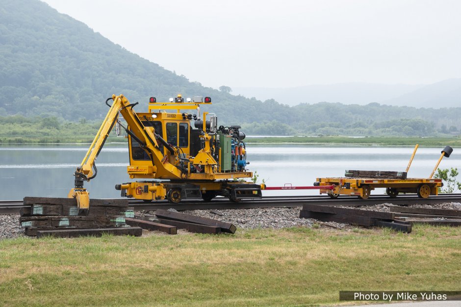 A tie crane removes the old ties off the roadbed and stacks them into small piles for later pickup.