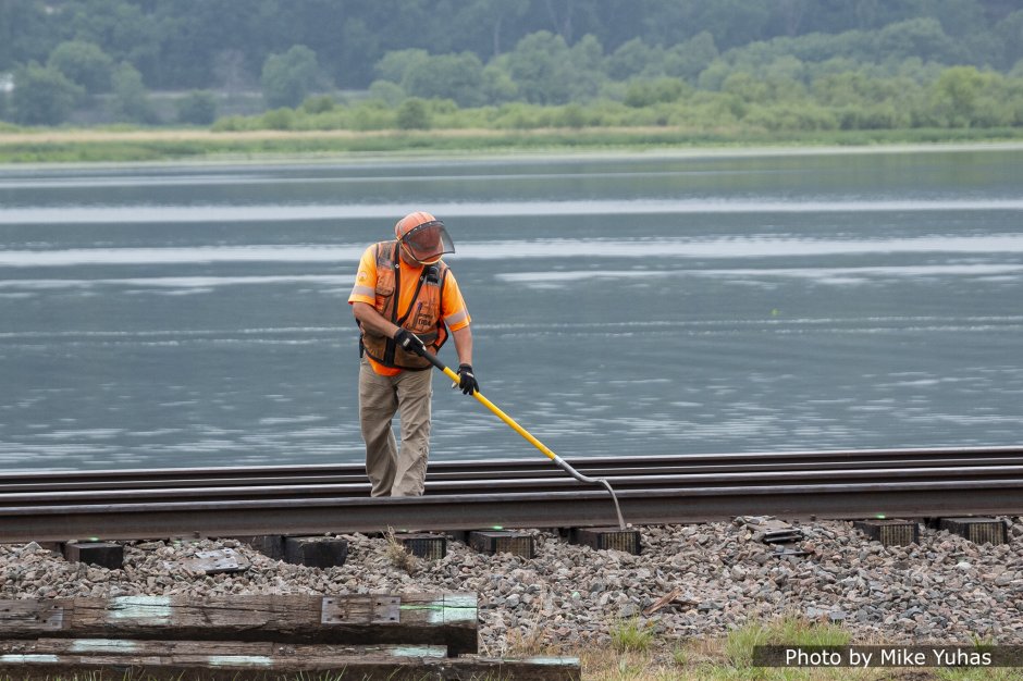 A worker manually removes any remaining ballast. This final cleaning step is important because the tie plate (next step) needs to rest on a clean tie surface.